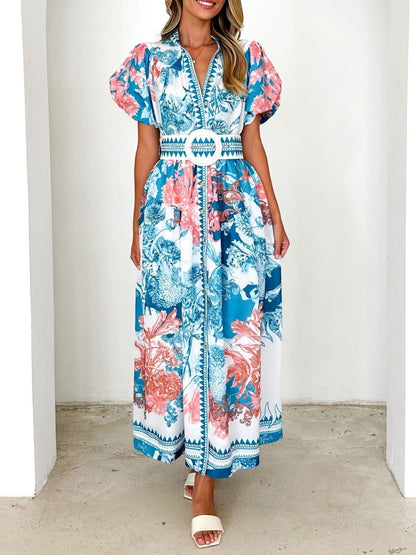 Model wearing a blue floral midi dress with puff sleeves and a side slit