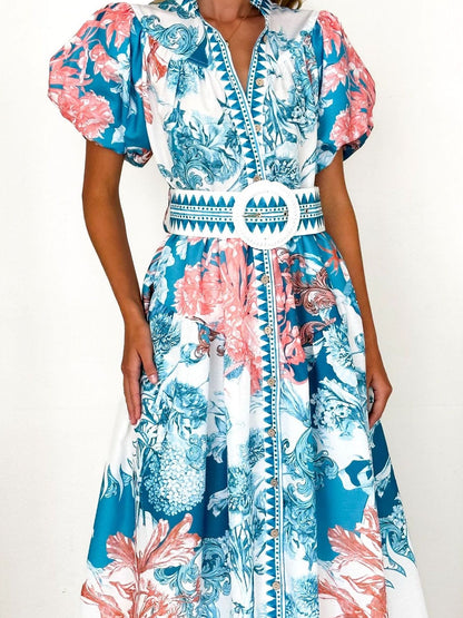 Model wearing a blue floral midi dress with puff sleeves and a side slit