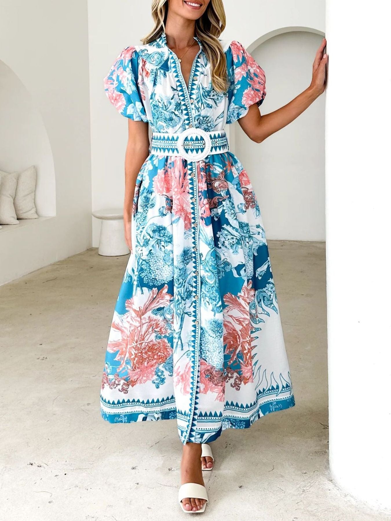 Model wearing a blue floral midi dress with puff sleeves and a side slit
