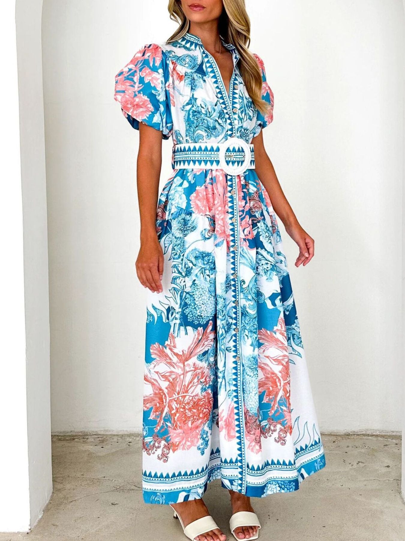 Model wearing a blue floral midi dress with puff sleeves and a side slit
