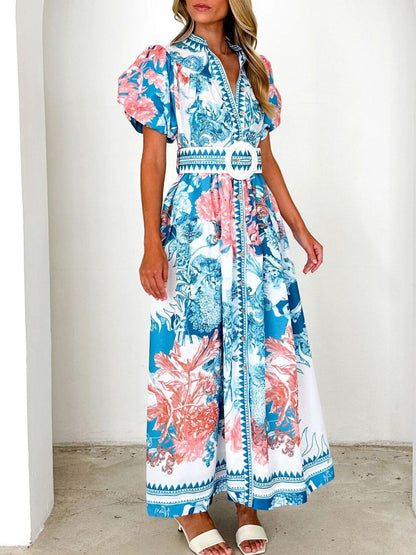 Model wearing a blue floral midi dress with puff sleeves and a side slit