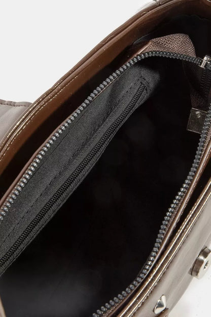 Detailed view of silver rivet studs on a black leather shoulder bag